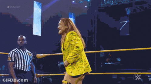 A Woman In A Yellow Suit Is Standing In A Wrestling Ring With A Referee GIF