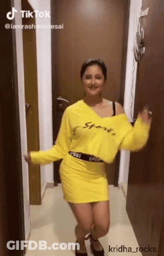 A Woman In A Yellow Sweater And Skirt Is Dancing GIF