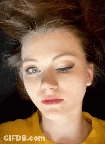 A Woman In A Yellow Sweater Is Making A Face GIF