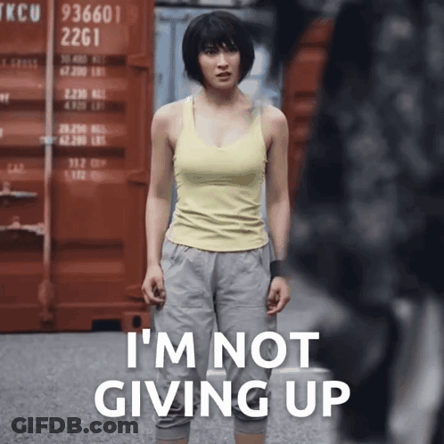 A Woman In A Yellow Tank Top Is Standing In Front Of A Red Container That Says Tkcu 2261 GIF