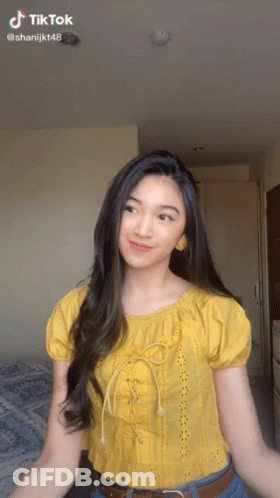 A Woman In A Yellow Top Is Dancing In A Room With A Tiktok Watermark GIF