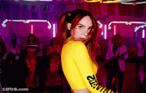 A Woman In A Yellow Top With The Word Caution On The Sleeves GIF