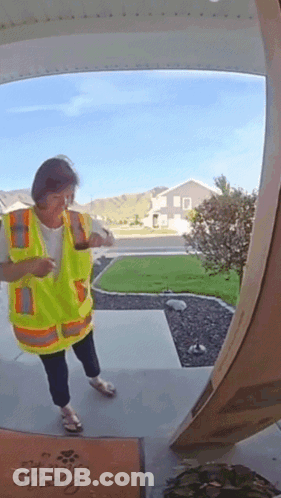 A Woman In A Yellow Vest Is Standing In Front Of A Door With A Welcome Mat GIF