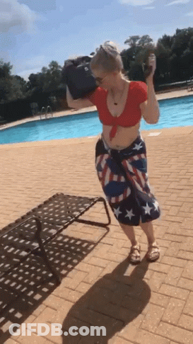 A Woman In An American Flag Skirt Is Standing By A Pool GIF