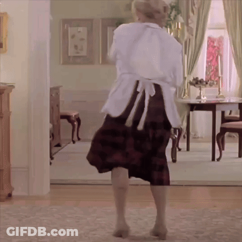 A Woman In An Apron Is Dancing In A Room GIF