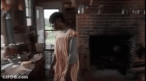 A Woman In An Apron Is Standing In A Kitchen GIF