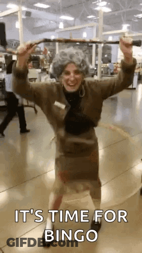 A Woman In An Elderly Woman Costume Is Holding A Cane And Dancing In A Store . GIF