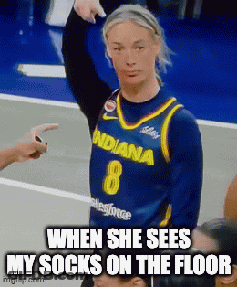 A Woman In An Indiana Basketball Jersey Is Pointing At Her Socks On The Floor GIF
