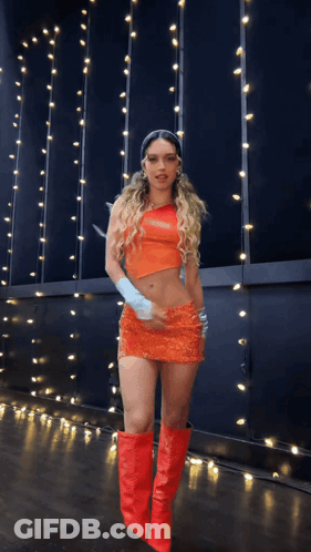 A Woman In An Orange Dress And Red Boots GIF