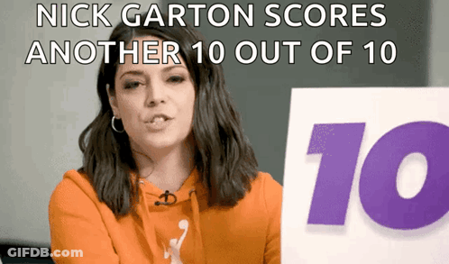 A Woman In An Orange Hoodie Holds Up A Sign That Says Nick Garton Scores Another 10 Out Of 10 GIF