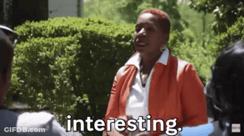 A Woman In An Orange Jacket Is Talking To A Man In A Park And The Woman Is Saying Interesting . GIF