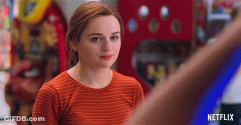 A Woman In An Orange Striped Shirt Is Standing In Front Of A Netflix Logo GIF