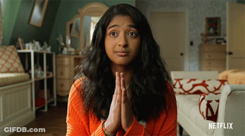 A Woman In An Orange Sweater Is Praying With Netflix Written On The Bottom Right GIF