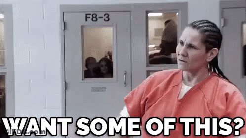 A Woman In An Orange Uniform Is Standing In Front Of A Door And Asking , `` Want Some Of This ? '' GIF