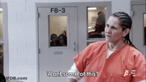 A Woman In An Orange Uniform Is Standing In Front Of A Door That Says F8-3 On It . GIF