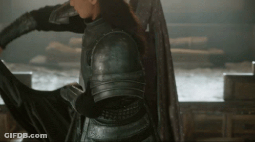 A Woman In Armor Is Holding A Sword In Her Hand GIF