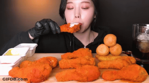 A Woman In Black Gloves Is Eating Fried Food GIF