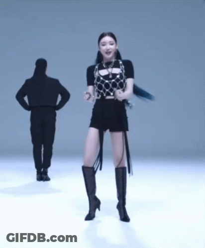 A Woman In Black Shorts And Boots Is Dancing In Front Of A Man GIF