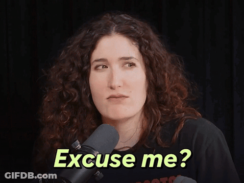 A Woman In Front Of A Microphone With The Words " Excuse Me " On Her Face GIF