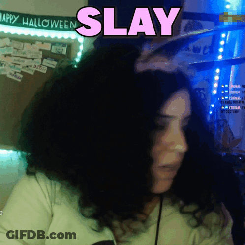 A Woman In Front Of A Sign That Says Happy Halloween And Says Slay GIF