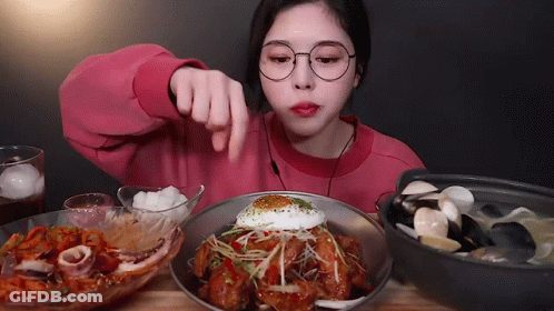 A Woman In Glasses Is Eating A Plate Of Food With A Fried Egg On Top GIF