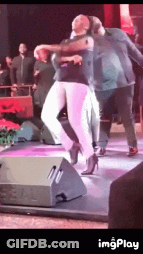 A Woman In High Heels Is Dancing On A Stage With A Man GIF