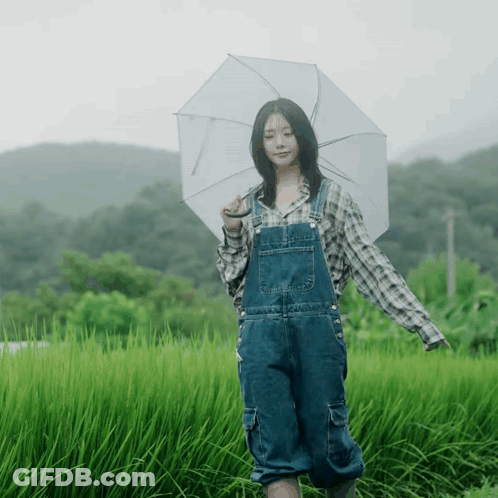 A Woman In Overalls Is Holding An Umbrella GIF