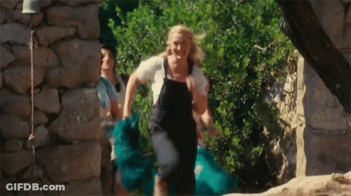A Woman In Overalls Is Running With A Blue Skirt GIF