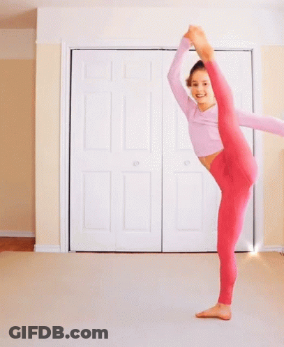 A Woman In Pink Pants Is Doing A Split In Front Of A White Door GIF