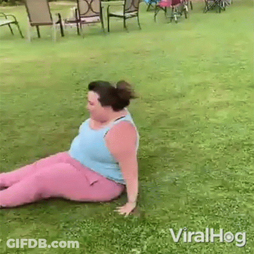 A Woman In Pink Pants Is Sitting On The Grass In A Yard . GIF