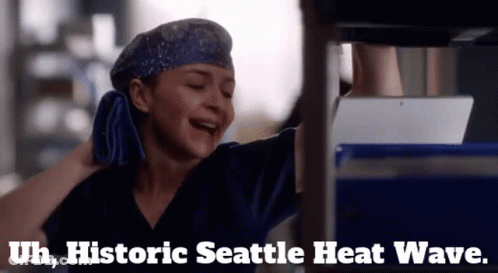 A Woman In Scrubs Is Laughing With The Words Historic Seattle Heat Wave Written Below Her GIF