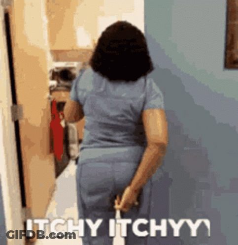 A Woman In Scrubs Is Walking Down A Hallway With The Words Itchy Itchyy Written On The Wall Behind Her GIF