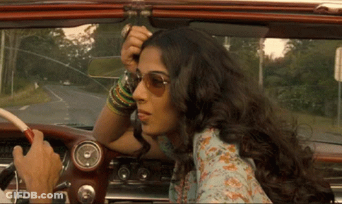 A Woman In Sunglasses Is Sitting In A Car With A Man Driving GIF