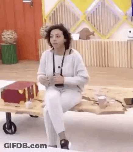 A Woman In White Pants Is Sitting On A Wooden Table . GIF