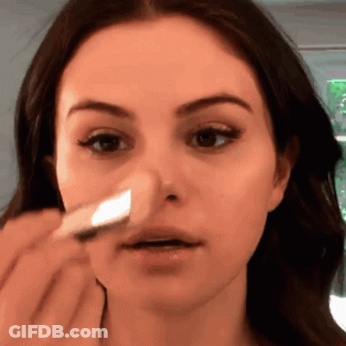 A Woman Is Applying A Sponge To Her Nose GIF