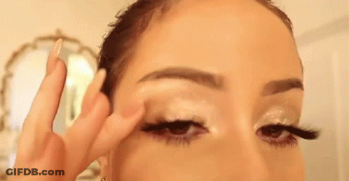 A Woman Is Applying Eye Shadow To Her Eye . GIF