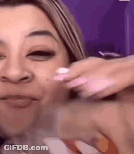 A Woman Is Applying Lotion To Her Face And Smiling GIF