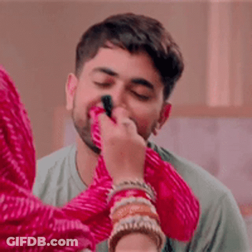 A Woman Is Applying Makeup To A Man 'S Face With A Brush . GIF
