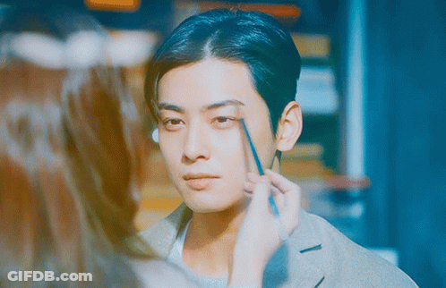 A Woman Is Applying Makeup To A Man 'S Face With A Pencil GIF