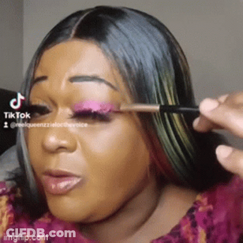 A Woman Is Applying Makeup To Her Eye With A Brush GIF