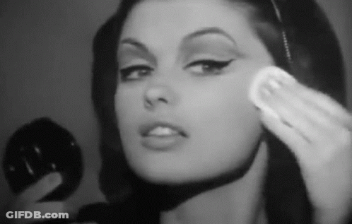 A Woman Is Applying Makeup To Her Face With A Sponge . GIF