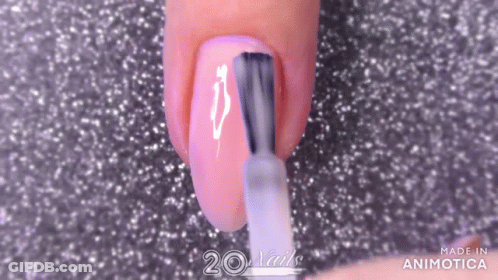 A Woman Is Applying Nail Polish To Her Nails With A Nail Brush . GIF