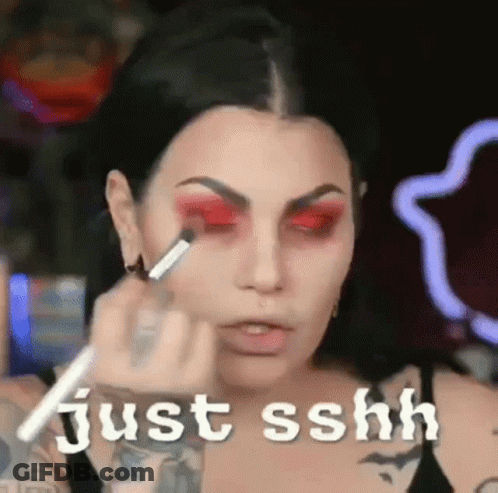 A Woman Is Applying Red Eye Shadow To Her Eyes . GIF