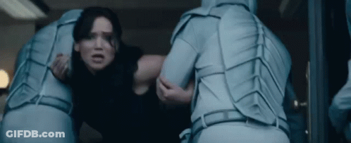 A Woman Is Being Held By A Man In A Blue Suit In A Room . GIF