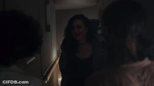 A Woman Is Being Held By Another Woman In A Dark Hallway GIF