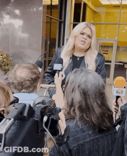 A Woman Is Being Interviewed By A Group Of Reporters Who Are Holding Microphones With The Letters Ctv On Them GIF