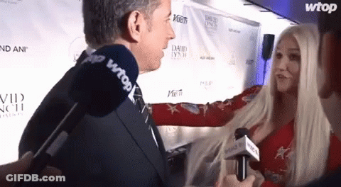A Woman Is Being Interviewed By A Man With A Microphone That Says Wtop On It GIF