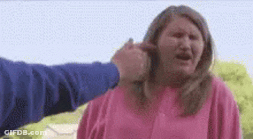 A Woman Is Being Punched In The Face By A Man In A Pink Shirt . GIF