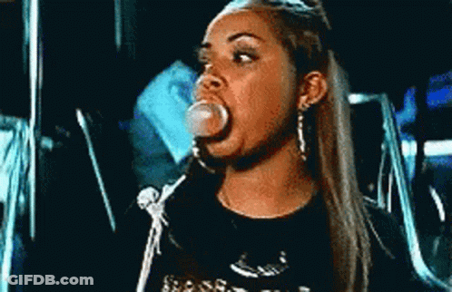 A Woman Is Blowing A Bubble With Her Tongue In A Dark Room . GIF
