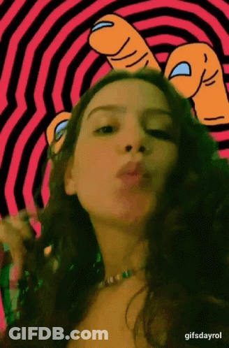 A Woman Is Blowing A Kiss In Front Of A Pink And Black Striped Background .. GIF